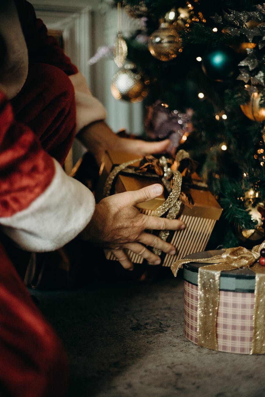 person wearing santa costume holding gold gift box