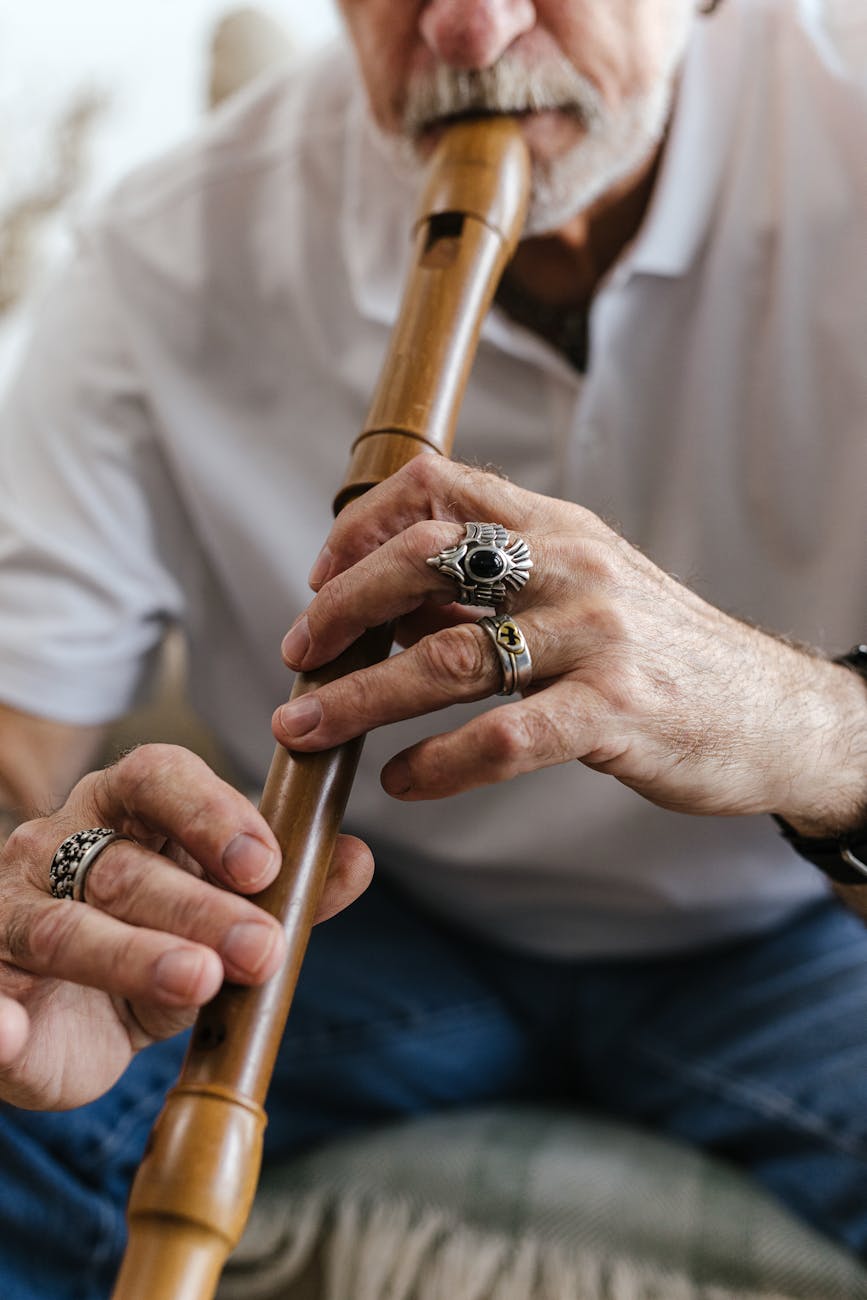 a bearded man in white shirt playing a flute