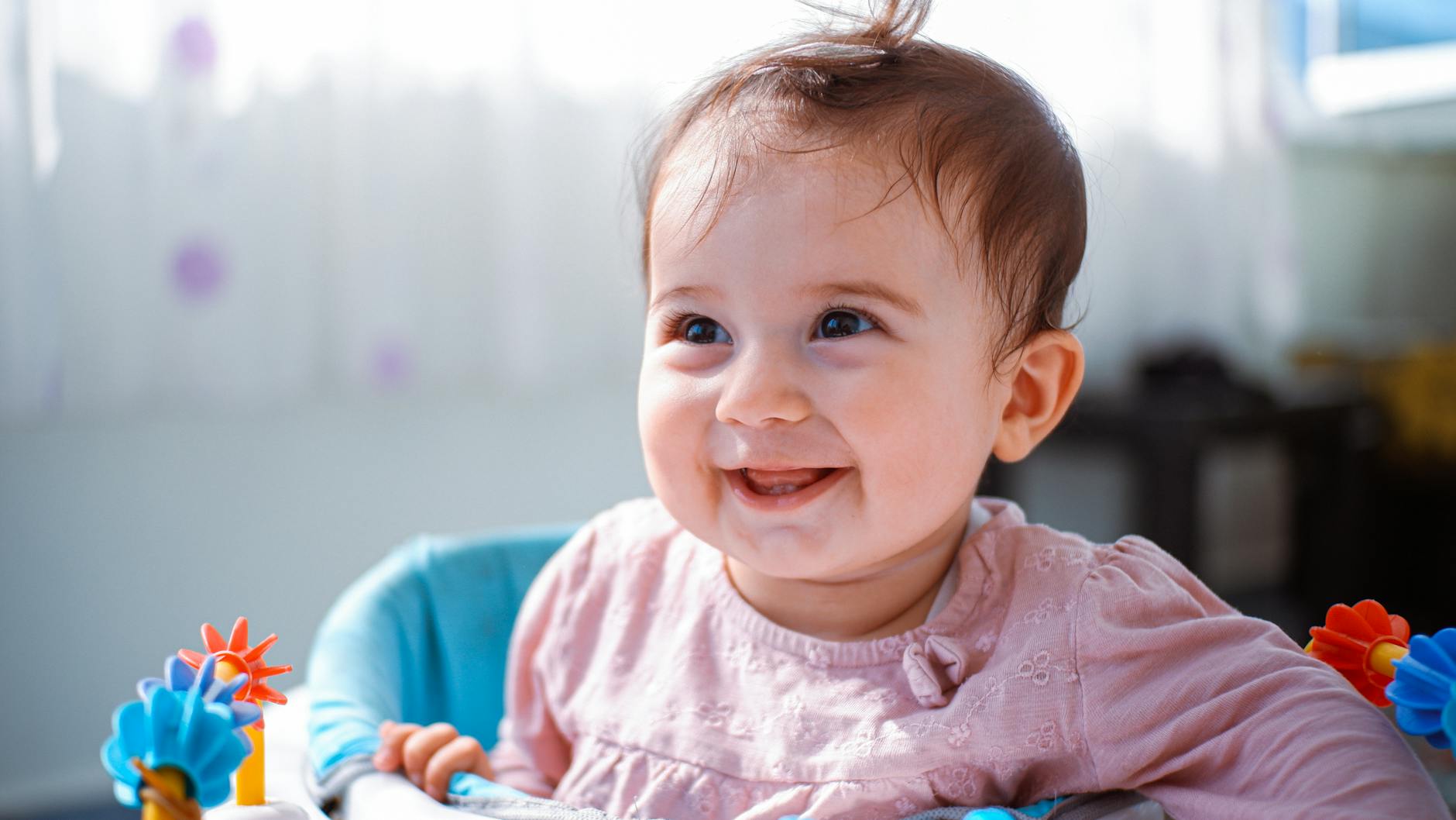 a baby smiles while sitting in a high chair